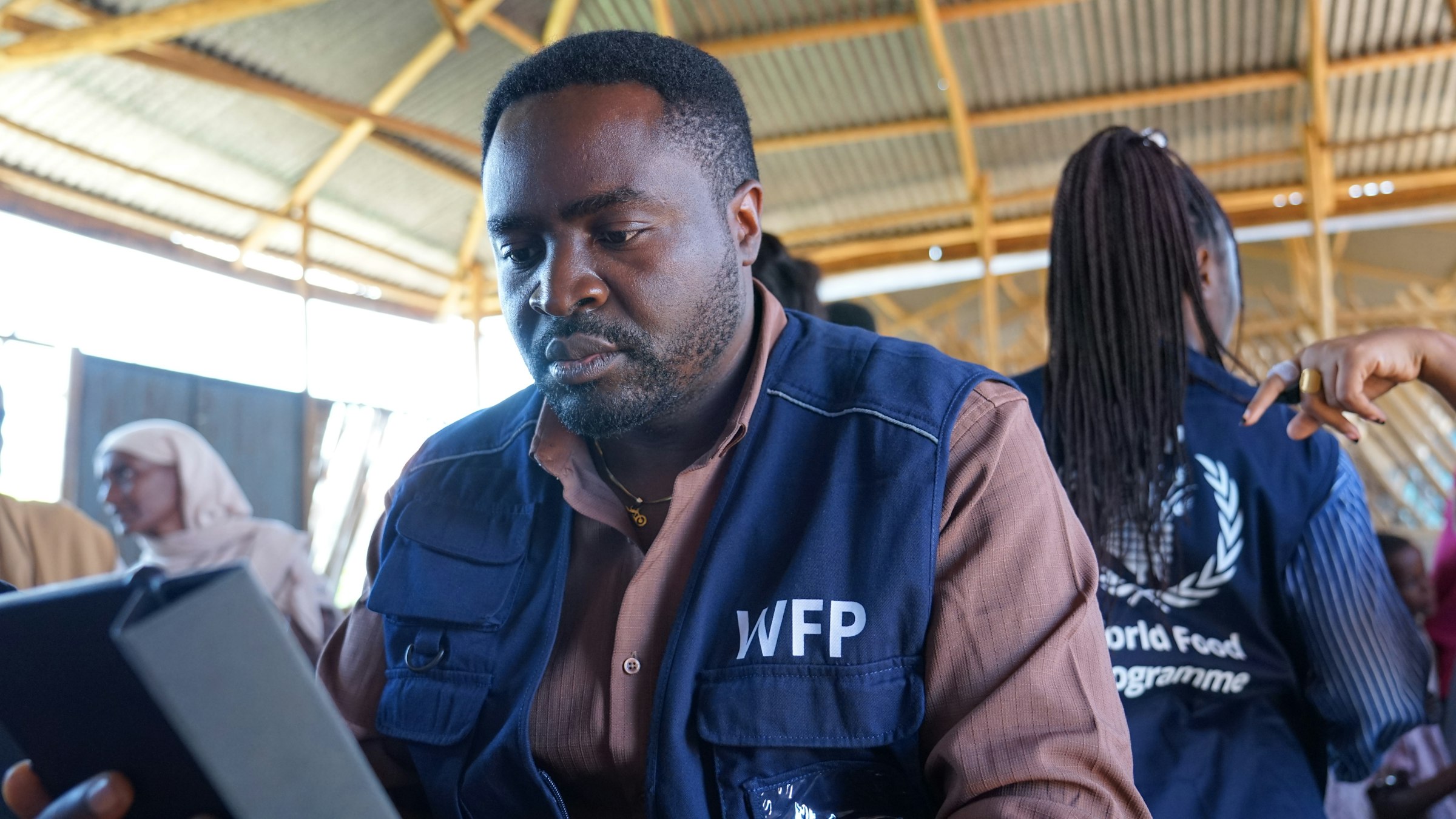 A World Food Programme field worker reviews a tablet during registration under a thatched-roof shelter at the Qoloji IDP camp in Ethiopia