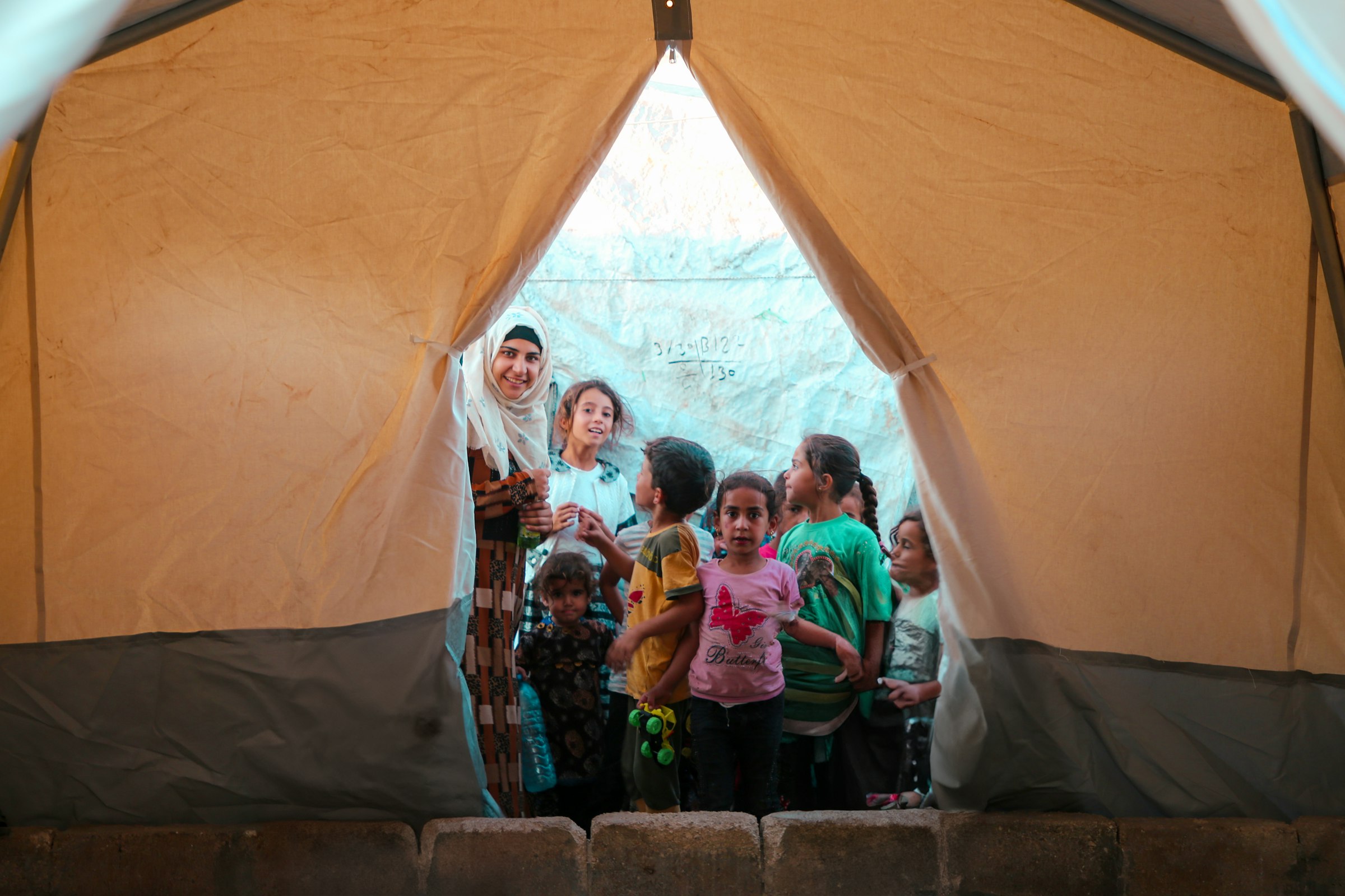 Woman and children gathered at the entrance of an aid tent, Syrian refugee camp