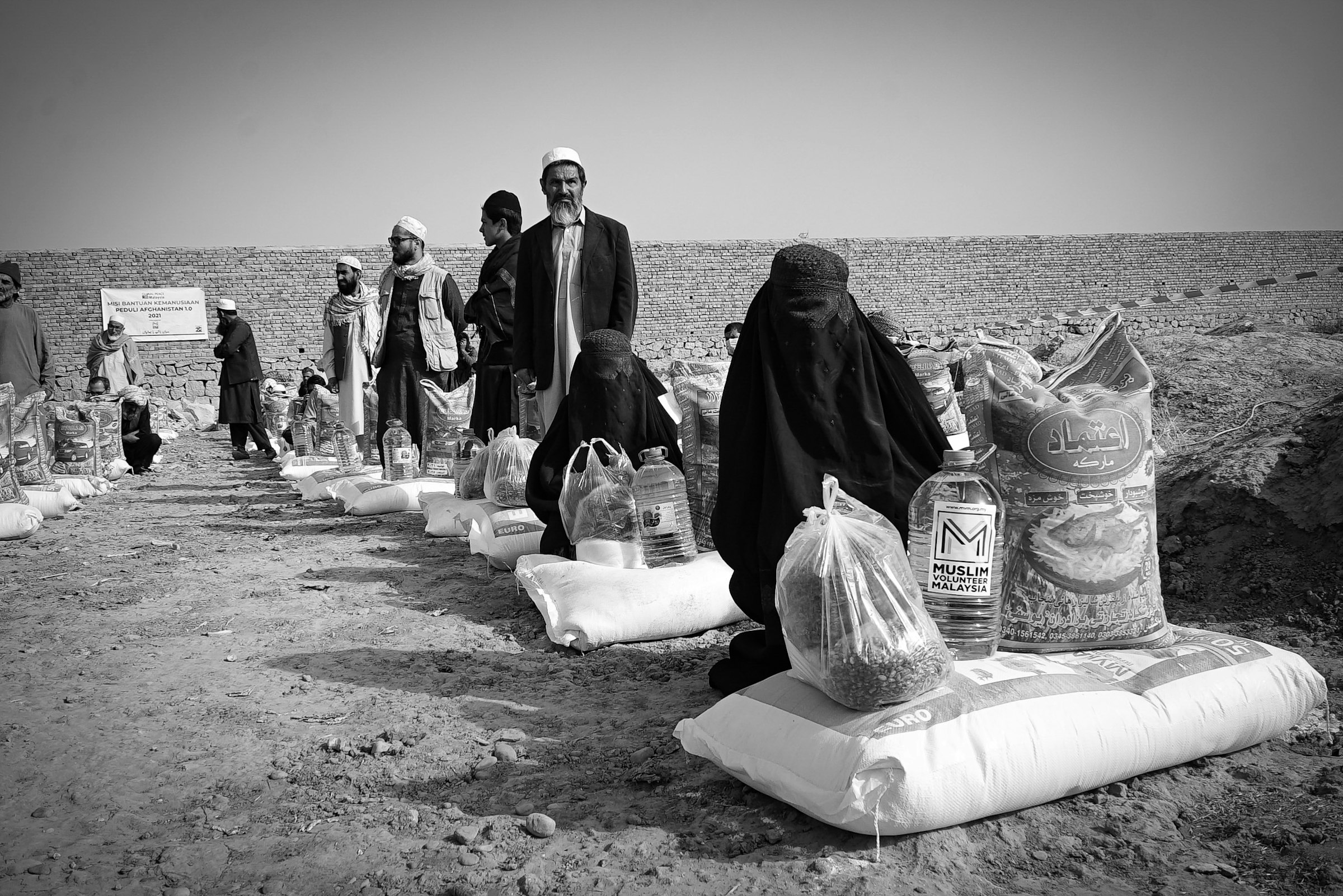 Families receiving food-aid sacks and supplies at a distribution point in Afghanistan