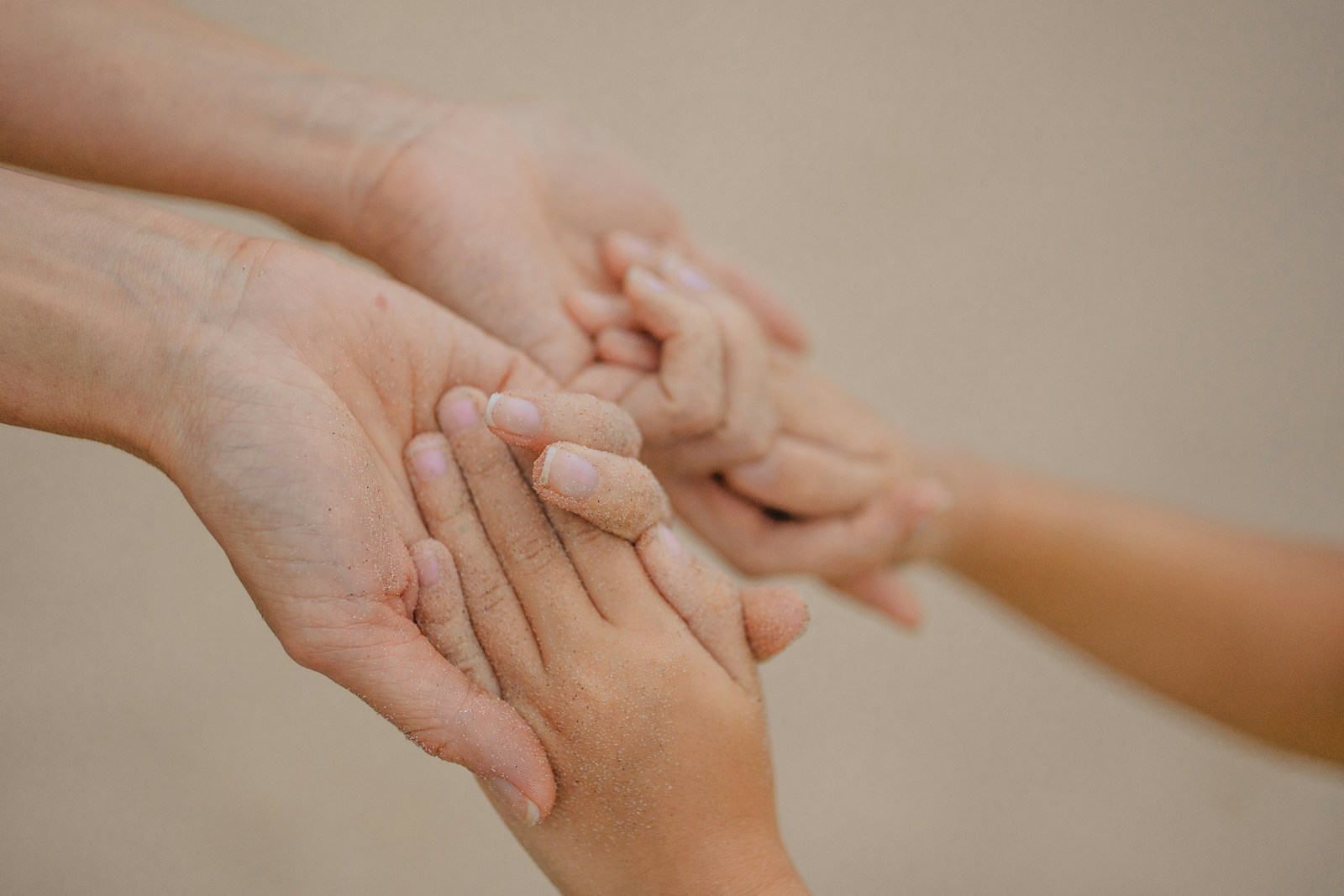 Close-up of an adult's hand gently holding a child's hand