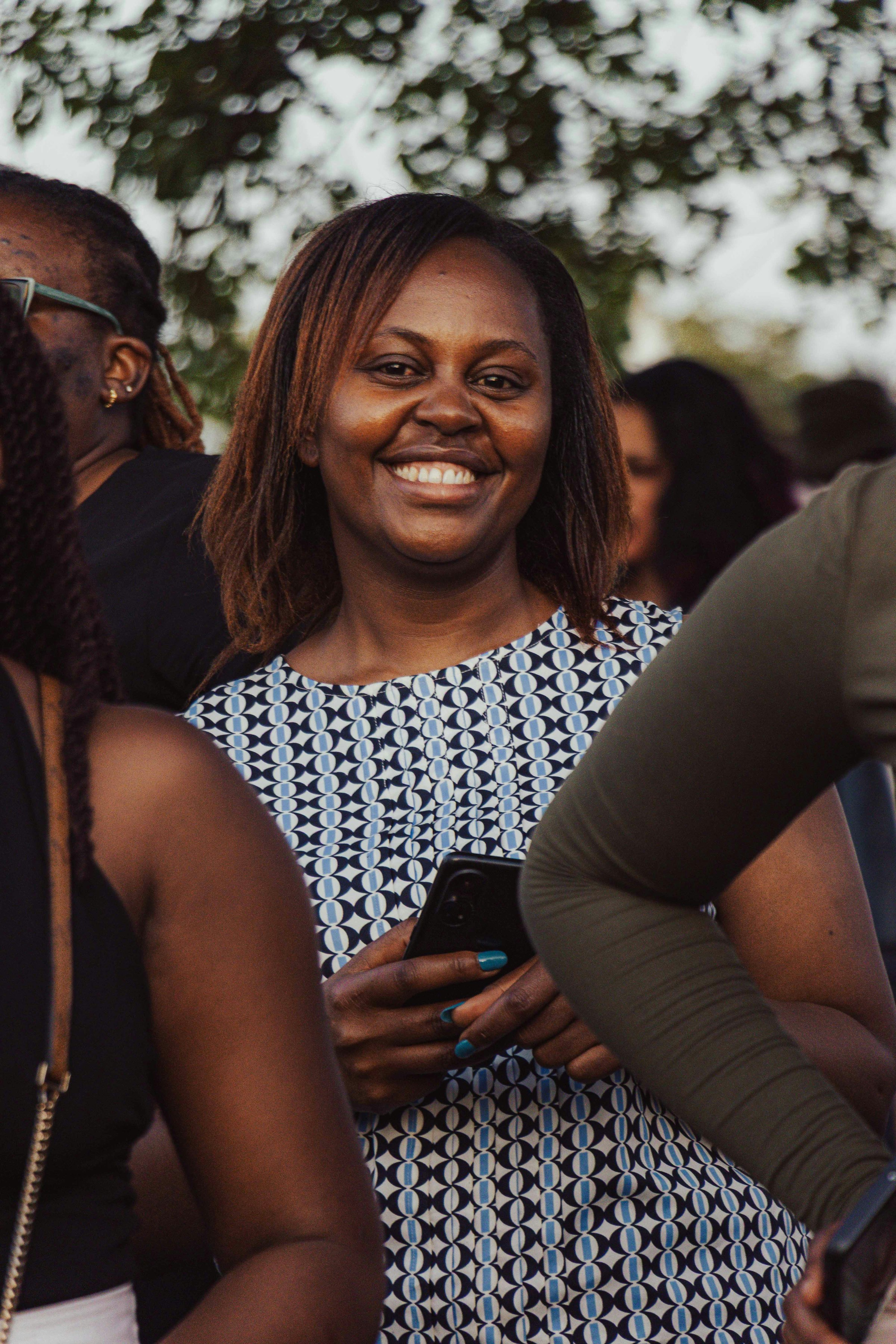 Woman outdoors in Kenya smiling while holding a smartphone