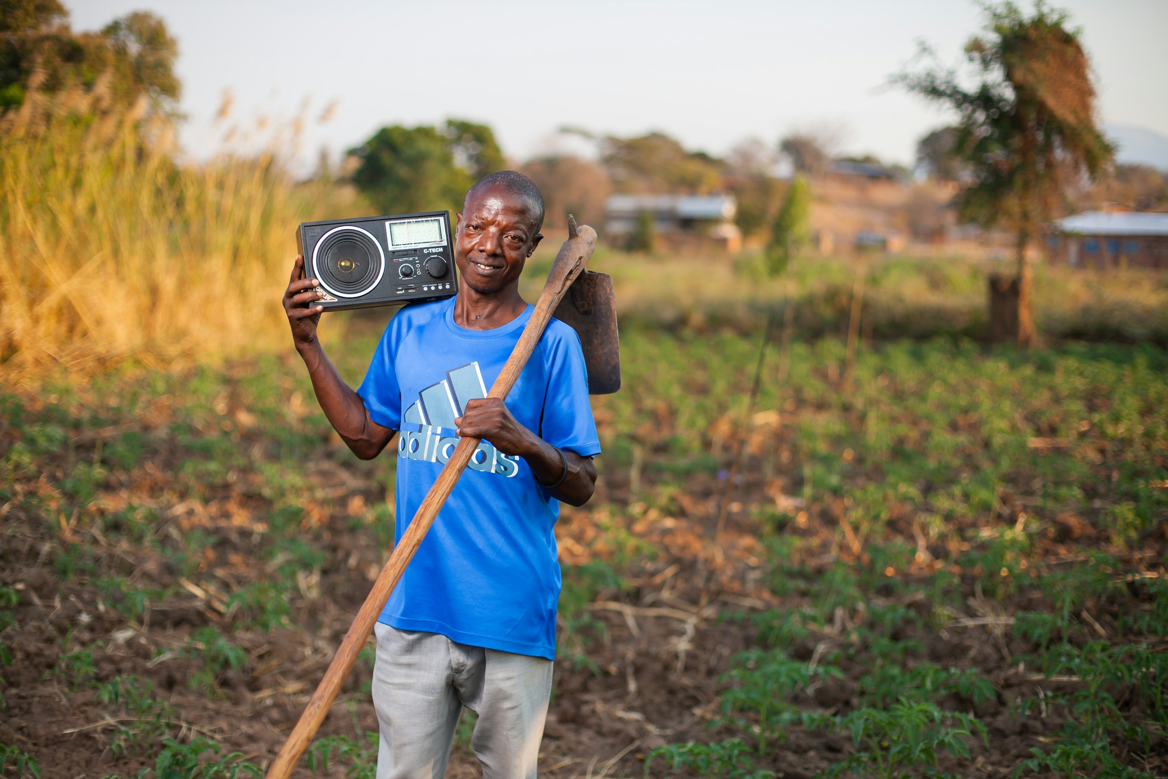 Farmer standing in a field holding a two-way radio, Malawi