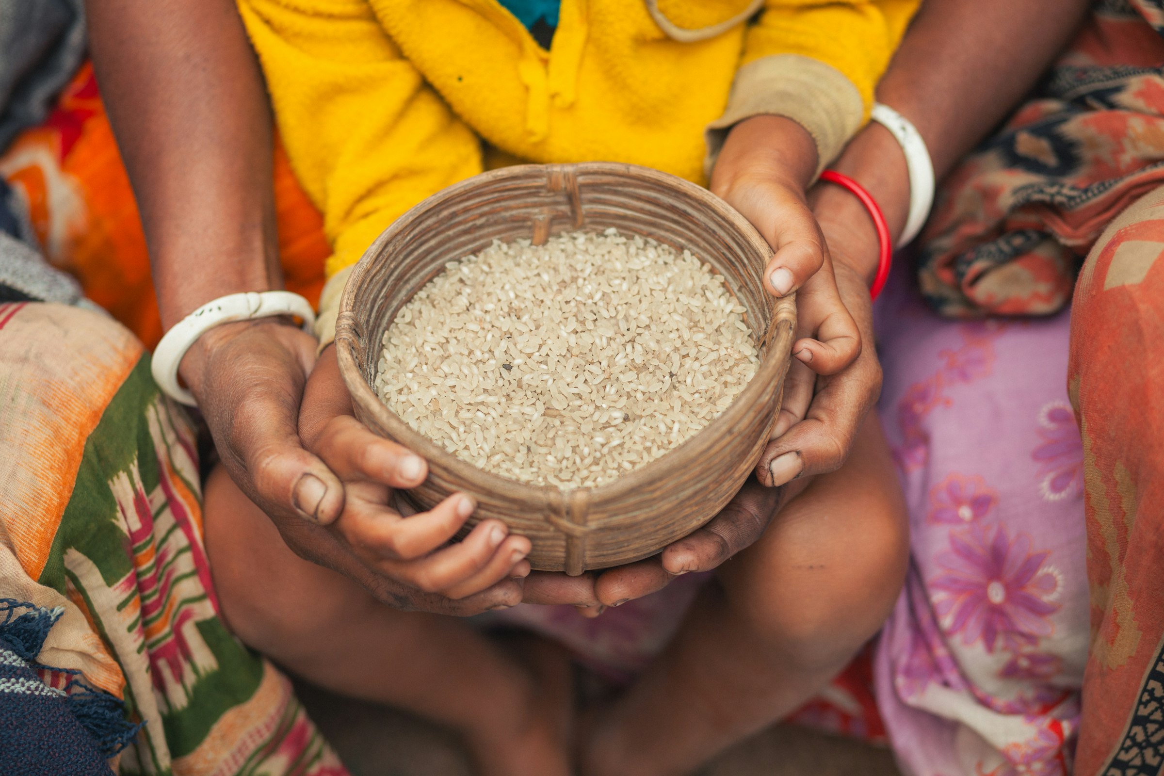 Adult hands holding a wooden bowl of rice for a child